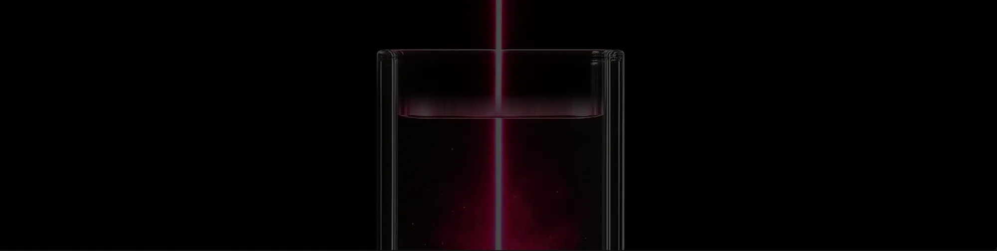 Pink laser beam ablating a metal target immersed in liquid inside a glass cuvette