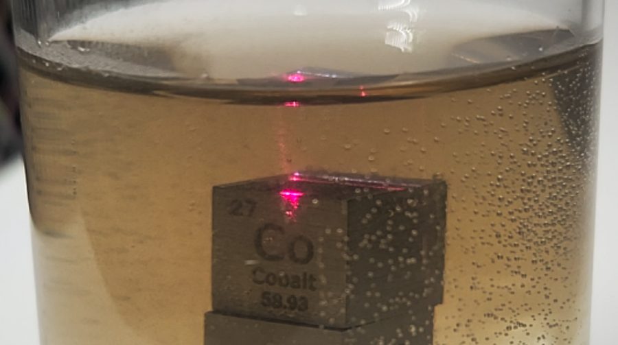 Cobalt cube submerged in liquid with a red pilot beam
