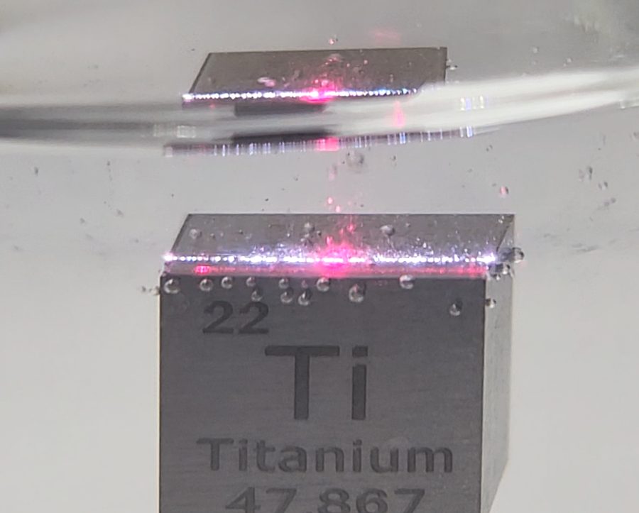 Titanium cube submerged in liquid with a laser spot